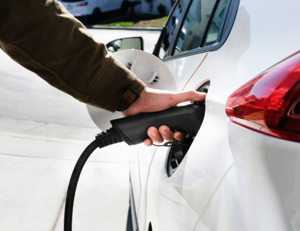 Man plugging charging cable into electric vehicle