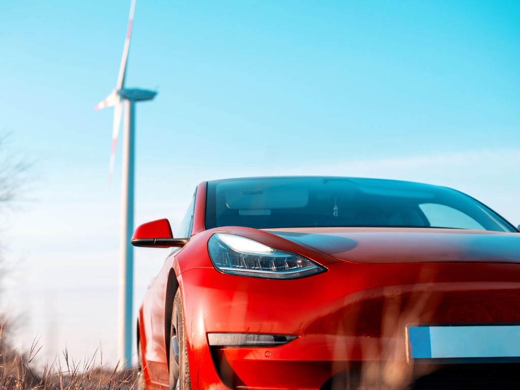 Tesla Model 3 parked next to wind turbine