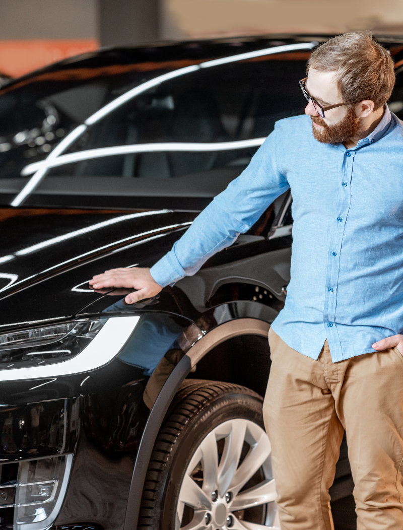 Man placing hand on shiny new black electric vehicle