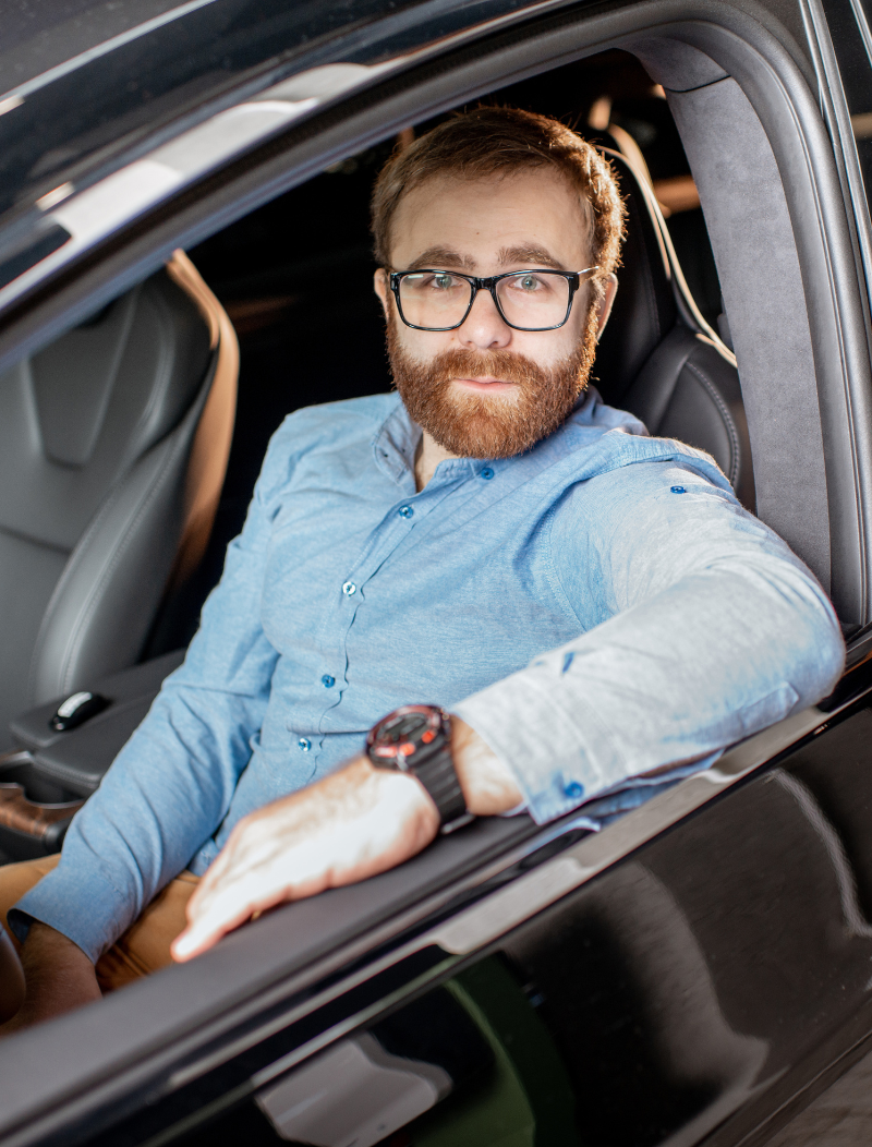 Man sitting in new car with arm resting on window
