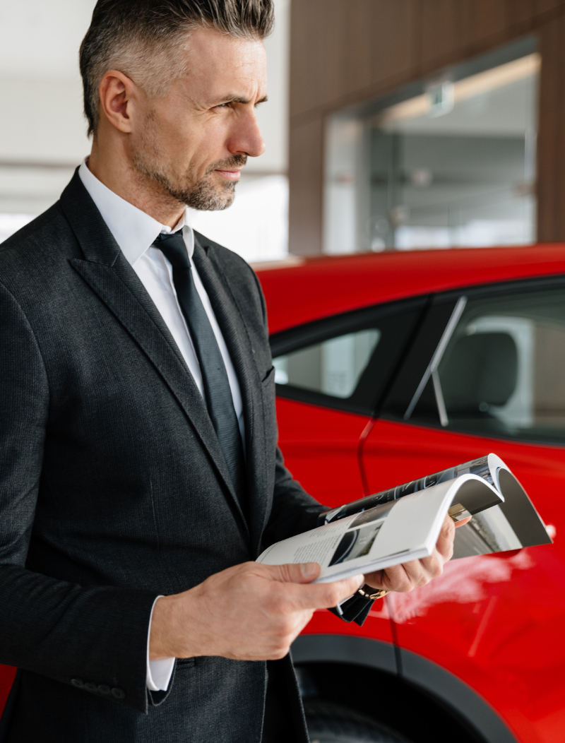 Suited man researching spec of car in a showroom