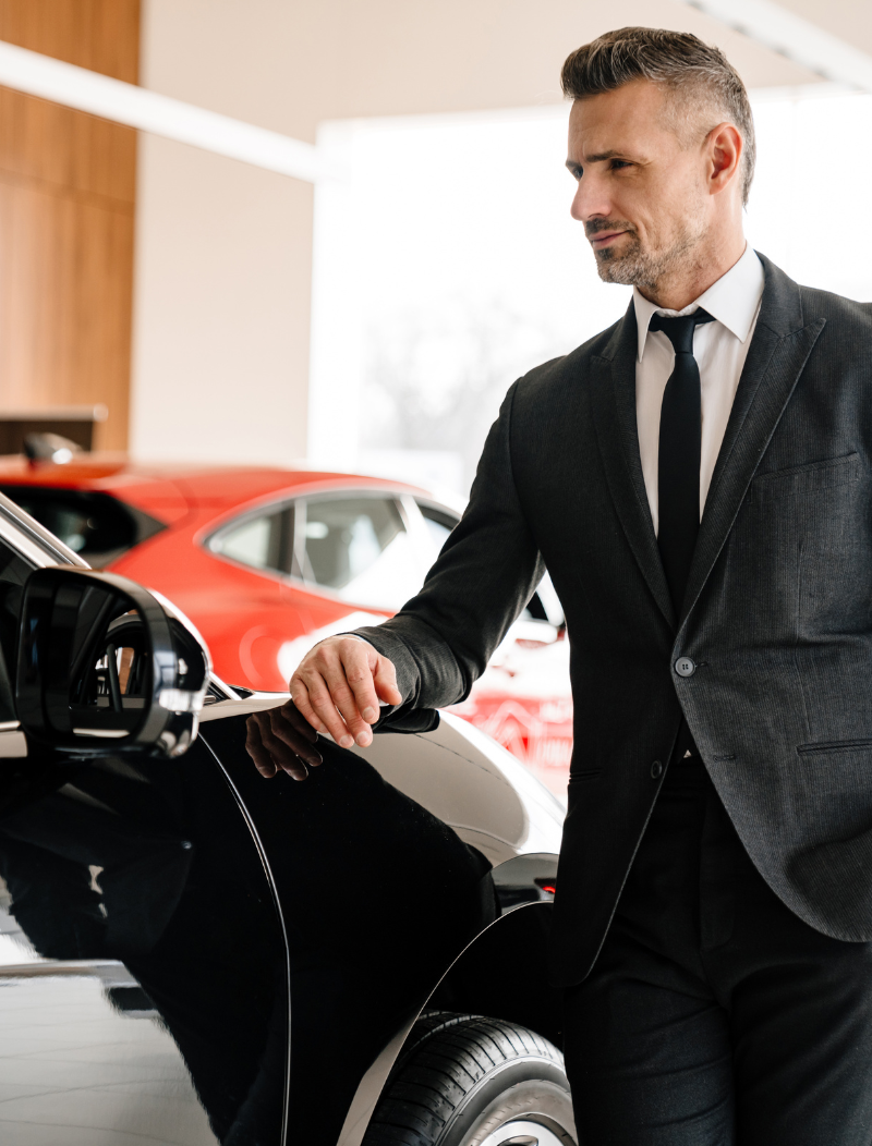 Man in suit leaning on bonnet of new car