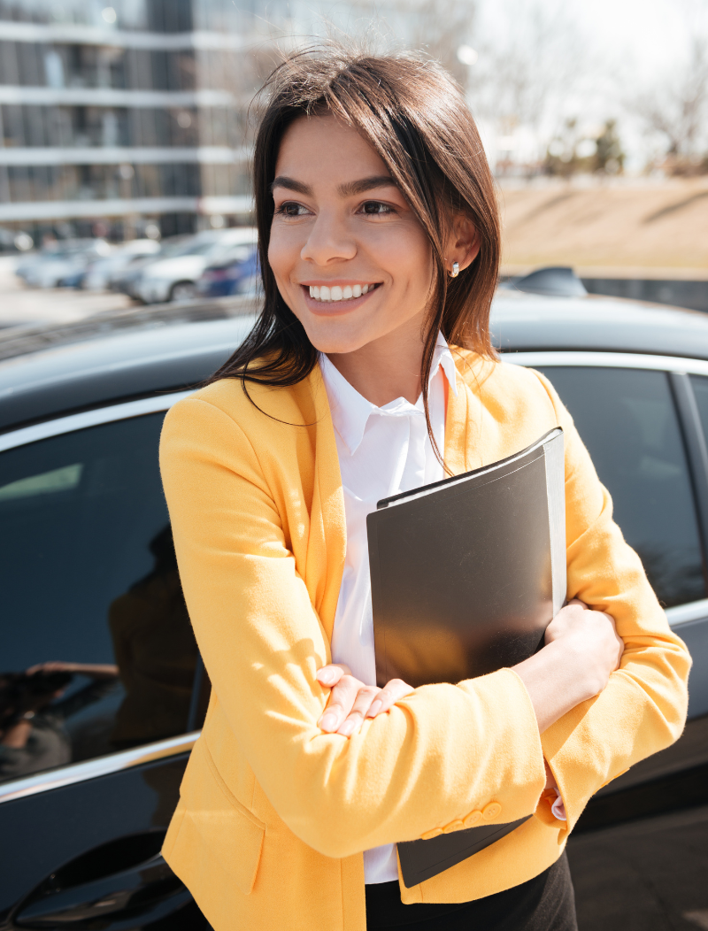 Woman in striking yellow blazer standing next to new vehicle