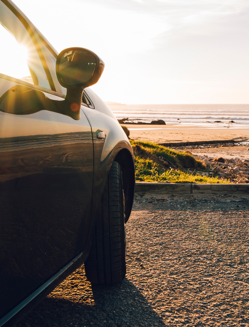 Car parked by the beach with sun out