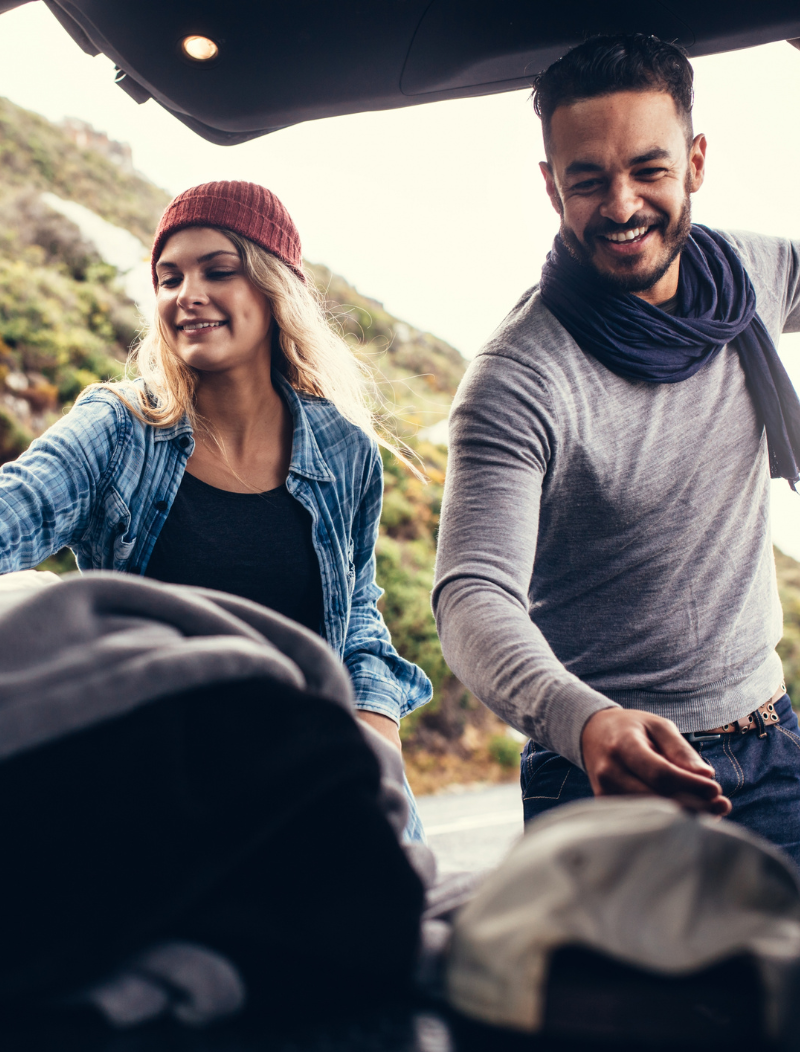 Young couple taking items out of boot of SUV
