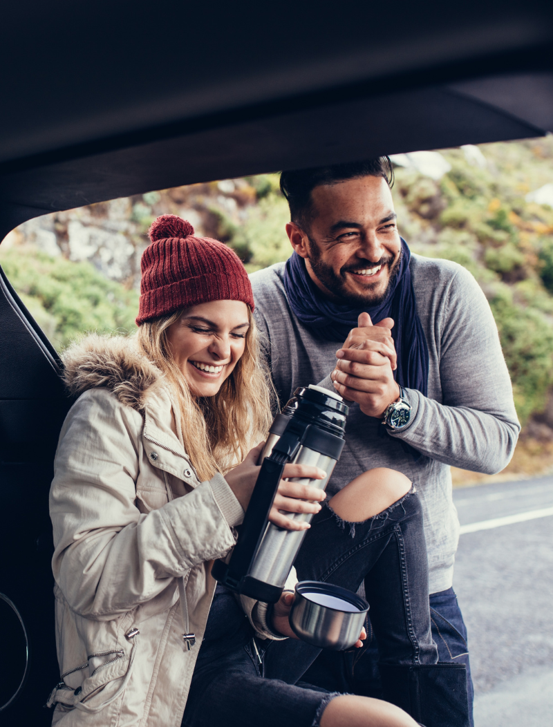 Young Couple with thermos in boot of car