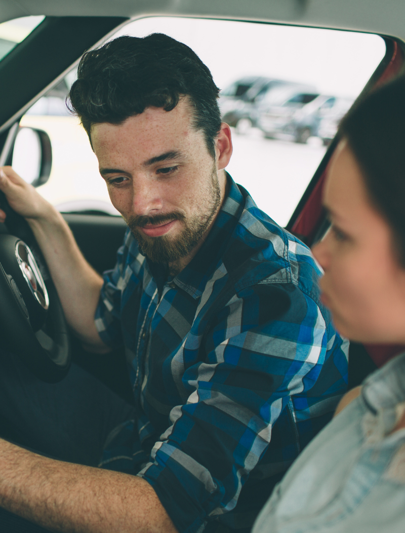 Young man and woman exploring features of car