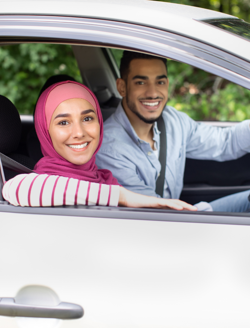Lady in headscarf leaning out of car window whilst husband drives
