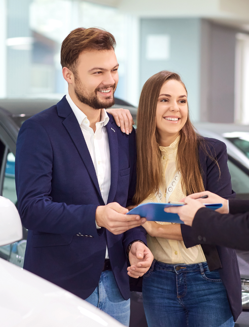 Young couple signing new car lease agreement