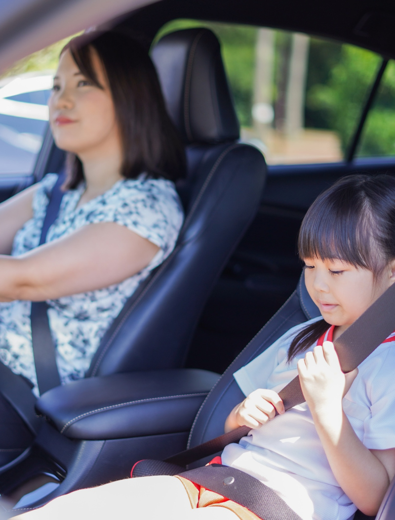 Mother and daughter setting off in new car, as child does up seatbelt