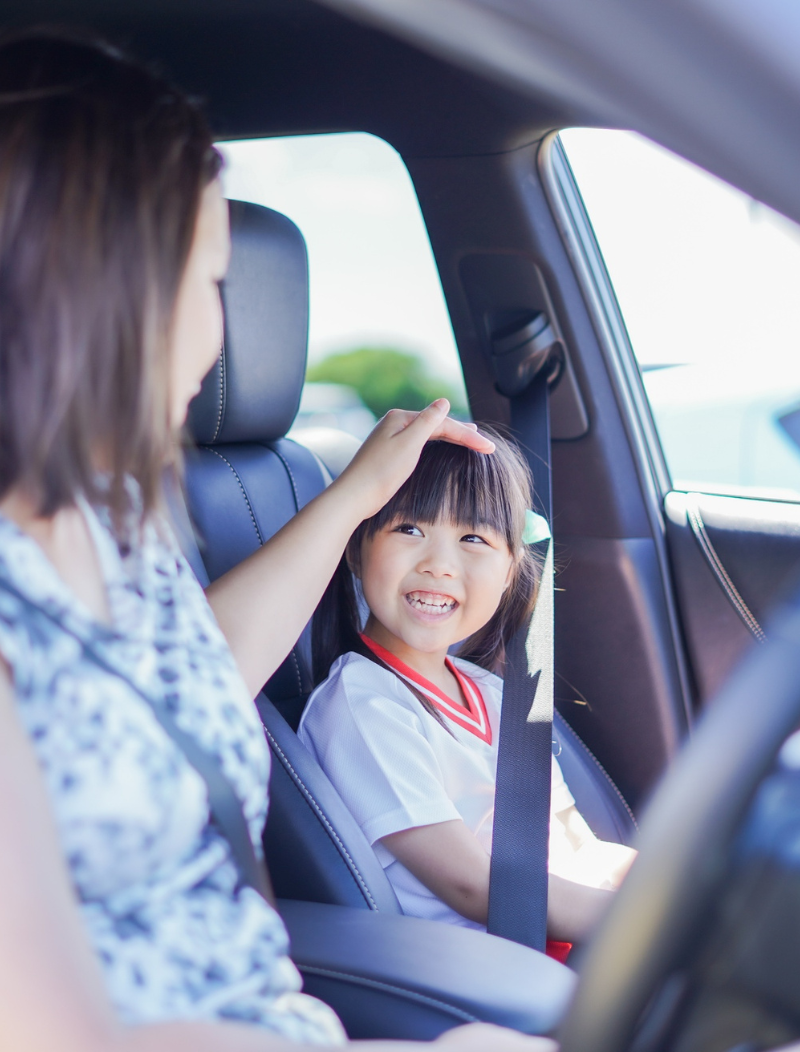 Mother pats head of asian child in car