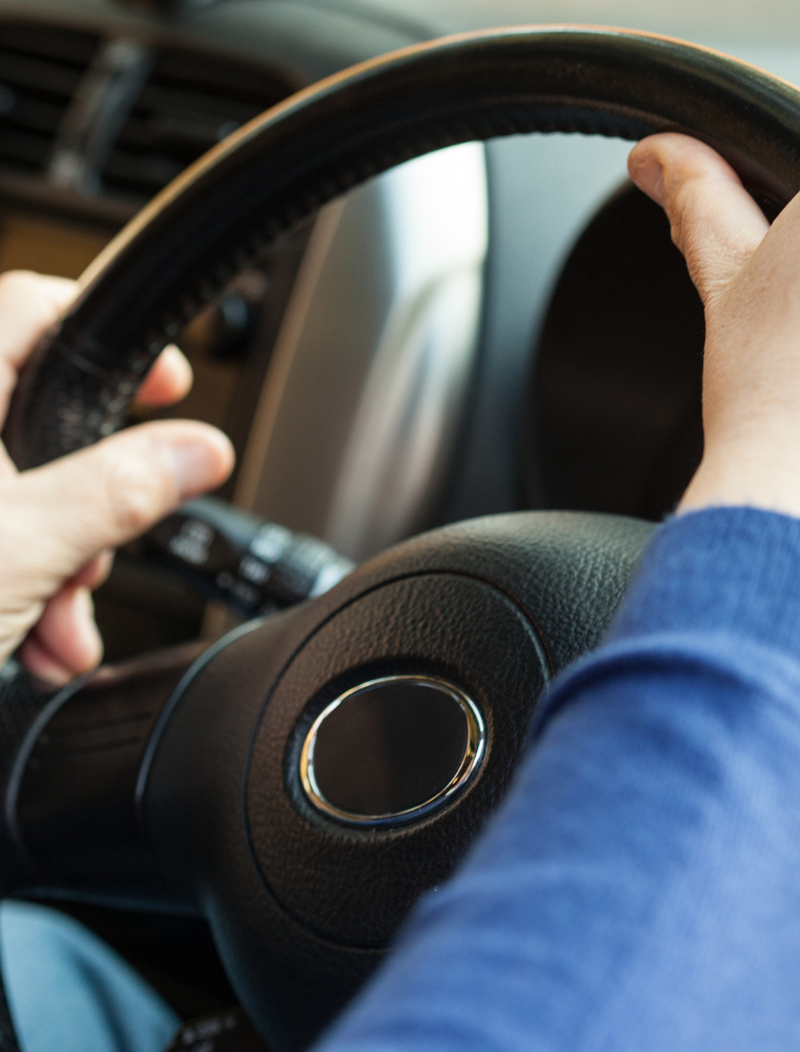 Man in blue jumper with hands on the wheel