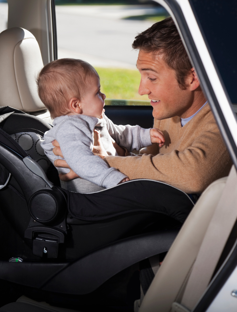 Man putting baby into rear facing car seat