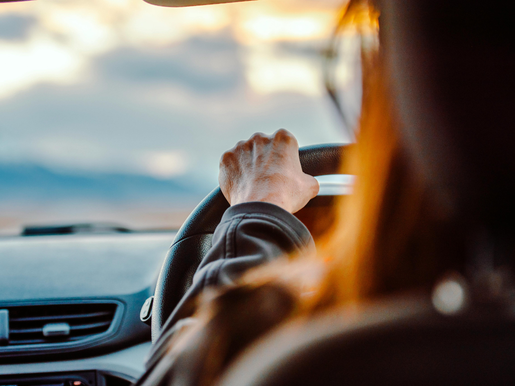 Woman driving car taken from rear passenger seat